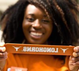 Image of a happy Long Horn student holding a Longhorn banner.