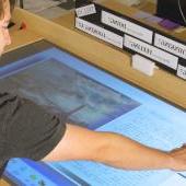 Student examines archived work on large touch screen display.