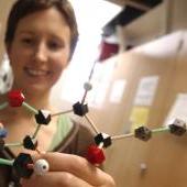 Student in lab holding a chemistry model.