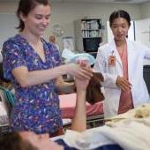 Nursing students receive instruction while helping a patient.